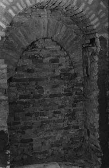 Fig. 27 - Chiesetta di S.Brizio. Parete est. Arco ogivale all'interno del muro. Nello stipite sud dell'arco esterno sono due fori per l'alloggiamento dei pali di chiusura della porta.