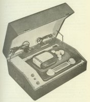 Apparecchio a nastro fonografico con amplificatore e altoparlante;  ben visibile la scatola contenente il nastro